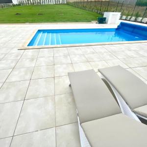 eine Terrasse mit zwei Stühlen und einem Swimmingpool in der Unterkunft Casa Iroko - a modern villa, with private pool, in a quiet area in Nadadouro