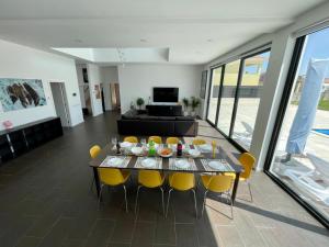 ein Wohnzimmer mit einem Tisch und gelben Stühlen in der Unterkunft Casa Iroko - a modern villa, with private pool, in a quiet area in Nadadouro + 34 Fotos