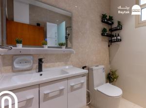a bathroom with a sink and a toilet and a mirror at بيتك - Baytak in Al Madinah +26 photos