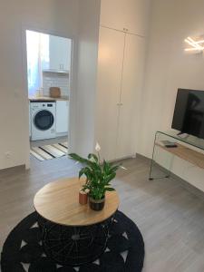 Una sala de estar con una mesa y un televisor. en Cosy studio in Portes de Paris, en Les Lilas