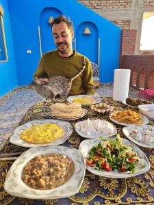 a man sitting at a table with plates of food at Golden Palace Garden in Luxor