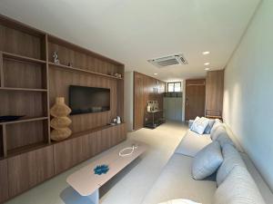 ein Wohnzimmer mit Sofa und Fernseher in der Unterkunft Amura Carneiros apartamento 3 quartos com piscina privativa in Praia dos Carneiros