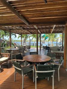 eine Außenterrasse mit Tischen, Stühlen und Meerblick in der Unterkunft Amura Carneiros apartamento 3 quartos com piscina privativa in Praia dos Carneiros