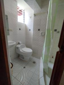 a white bathroom with a toilet and a shower at Kuntur House Machupicchu in Machu Picchu