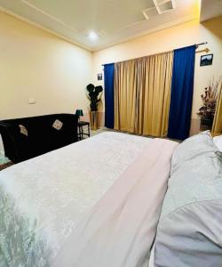 a bedroom with a large white bed with blue curtains at The Grand stay Topcity-1 Islamabad in Islamabad