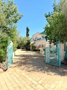 a gate to a driveway with trees and a building at VILLA 34 - 4 Masters, Moroccan Charm & Modern Comfort with Private Pool in Marrakesh