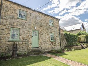 an old stone house with a green door at Loft Cottage in Bedale