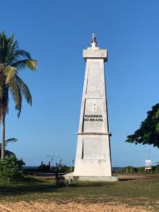 a lighthouse on the beach with a palm tree at Raizes da Terra - Ponta do Corumbau in Corumbau
