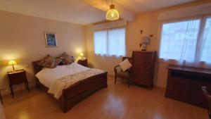 a bedroom with a bed and a dresser and windows at La terrasse de Jeanne in Millau