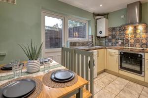 a kitchen with a wooden table with plates on it at Comfortable 2 Bedroom Cottage with Driveway and Pet Friendly Stay in Partington