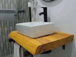 a white sink on a wooden counter in a bathroom at NC Hotel in Bragança Paulista