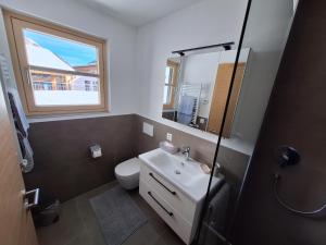 um banheiro com vaso sanitário, pia e janela em chalet10 em Samnaun