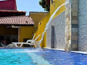 a swimming pool with a fountain in front of a building at Casa de temporada Bem-Te-Vi in Porto Seguro