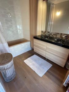 a bathroom with a tub and a sink and a mirror at La Lutine in Luc-sur-Mer