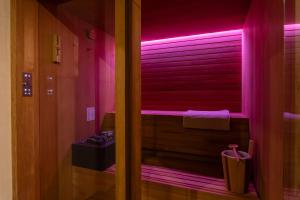 a bathroom with pink lighting and a window with shutters at ELESOR & Spa in Modica +11 photos