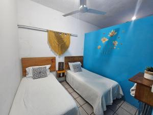 a room with two beds and a blue wall at LOS SAUCES STUDIO in Puerto Vallarta
