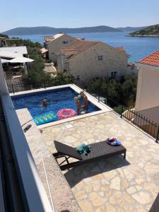 a swimming pool with two people playing in it at Apartment White House in Vinišće