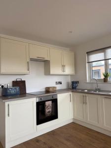 a kitchen with white cabinets and a dog on the oven at West Riverside Farm in Stirling