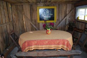 a table in a wooden cabin with a vase of flowers on it at Hallikivi Tourist Farm in Vennarti