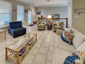 a living room with a couch and chairs and a staircase at 3 Sheets To the Zin in Port Aransas