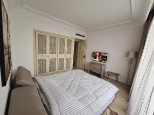 a white bedroom with a bed and a tv at Confortable appartement S 2 à marina HAMMAMET in Hammamet Sud