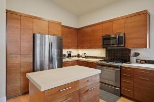 a kitchen with wooden cabinets and a stainless steel refrigerator at Dwell 30 Day Minimum in Bend +36 photos