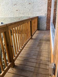 a wooden balcony with a wooden rail and a brick wall at Downtown Lynchburg REAL loft living Va Virginia in Lynchburg