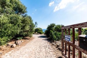 una puerta en un camino de tierra con un cartel en ella en Haus In Sant Antioco Mit Überdachtem Parkplatz, en Crisionis