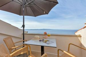a table and chairs with an umbrella on a balcony at Villa Margitta Mit Pool, Tennisplatz Und Meerblick in Drasnice