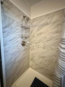 a bathroom with a shower with white marble at Cozy Bungalow 3bdrm 2 and a half bath Hot Tub in Little Rock