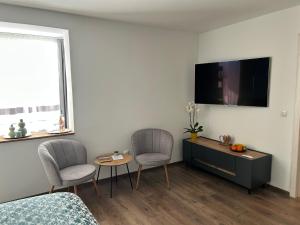 a living room with two chairs and a tv on the wall at VYO Studio in Braşov