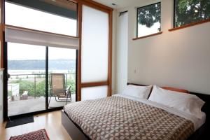 a bedroom with a bed and a balcony with a chair at Bridge View Loft 30 Day in Hood River