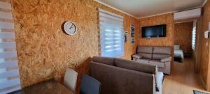 Una sala de estar con un sofá y un reloj en la pared. en Family Surf Home - Bungalows, en Mafra