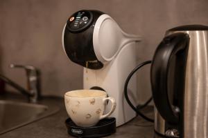 a coffee maker is pouring coffee into a cup at Bright Vilnius Center Apartment in Vilnius