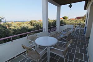 een veranda met een tafel en stoelen en de oceaan bij VILLA RELAX in Skala Kallirakhis