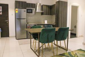 a kitchen with a table with green chairs and a refrigerator at Luxurious inn at Embassy Gardens in Accra