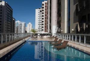 a swimming pool with chairs and tables on a building at S4 Hotel SUÍTE 1120 in Brasília
