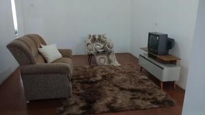 a living room with a chair and a tv at Apartamento Central in Triunfo