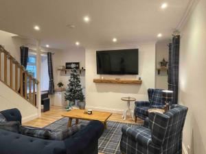 un salon avec deux canapés et une télévision dans l'établissement Modern cottage with hot tub, à Kirkcudbright