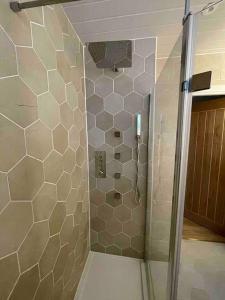 une douche avec une porte vitrée dans une salle de bain dans l'établissement Modern cottage with hot tub, à Kirkcudbright