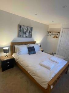 une chambre avec un grand lit avec des draps et des oreillers blancs dans l'établissement Modern cottage with hot tub, à Kirkcudbright