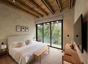 a bedroom with a large bed and a large window at Riverside Haven Elegant House with Serene Forest in San Simon El Alto