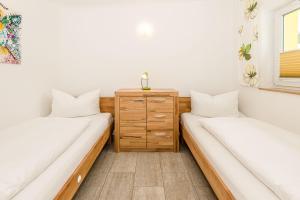 two beds in a room with a wooden dresser at Bungis - 28 Ferienhäuser Am Grimnitzsee G3 in Joachimsthal