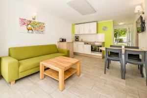 a living room with a green couch and a table at Bungis - 28 Ferienhäuser Am Grimnitzsee G3 in Joachimsthal
