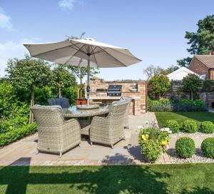 un patio avec une table, des chaises et un parasol dans l'établissement Peaceful Rural Cottage with hot tub, à Fenton