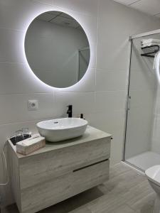 un bagno bianco con lavandino e specchio di Alcazaba II tourist apartment a Badajoz