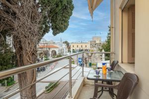 a table and chairs on a balcony with a view of a street at Thea in Kos