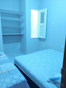 a blue room with a bed and a window at Kitipê Arretado da Peste in Aquiraz