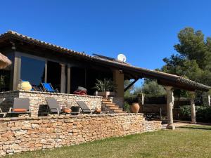 a house with a stone wall and chairs at LO CLAUSTRE DEL DELTA- LUX FINCA in Delta del Ebro - FINCA PRIVADA -NO HAY NINGUN SERVICIO HOTELERIA- SOLO ALOJAMIENTO in Sant Carles de la Ràpita