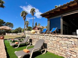 a row of lounge chairs on a lawn with palm trees at LO CLAUSTRE DEL DELTA- LUX FINCA in Delta del Ebro - FINCA PRIVADA -NO HAY NINGUN SERVICIO HOTELERIA- SOLO ALOJAMIENTO in Sant Carles de la Ràpita